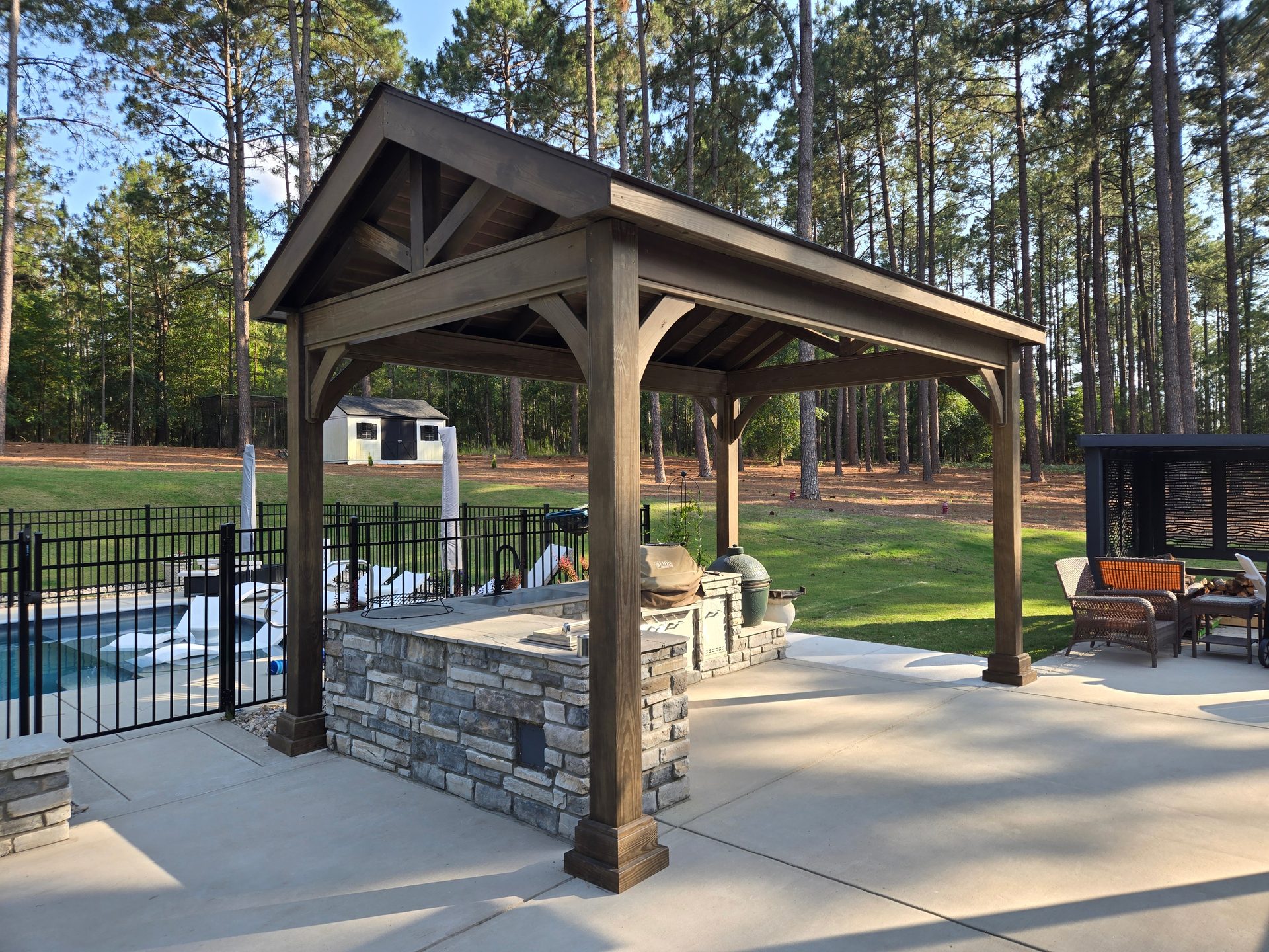 Wood pavilion and stone kitchen beside a pool at golden hour