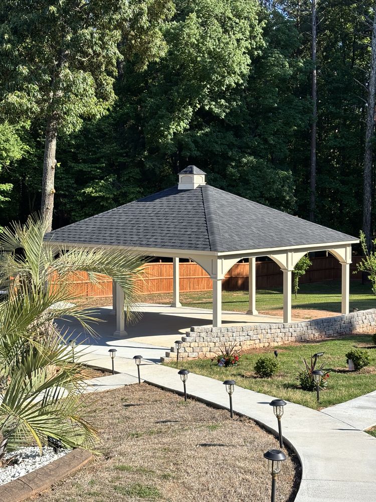 Poolside patio with a black metal privacy screen, landscaping, and a covered structure
