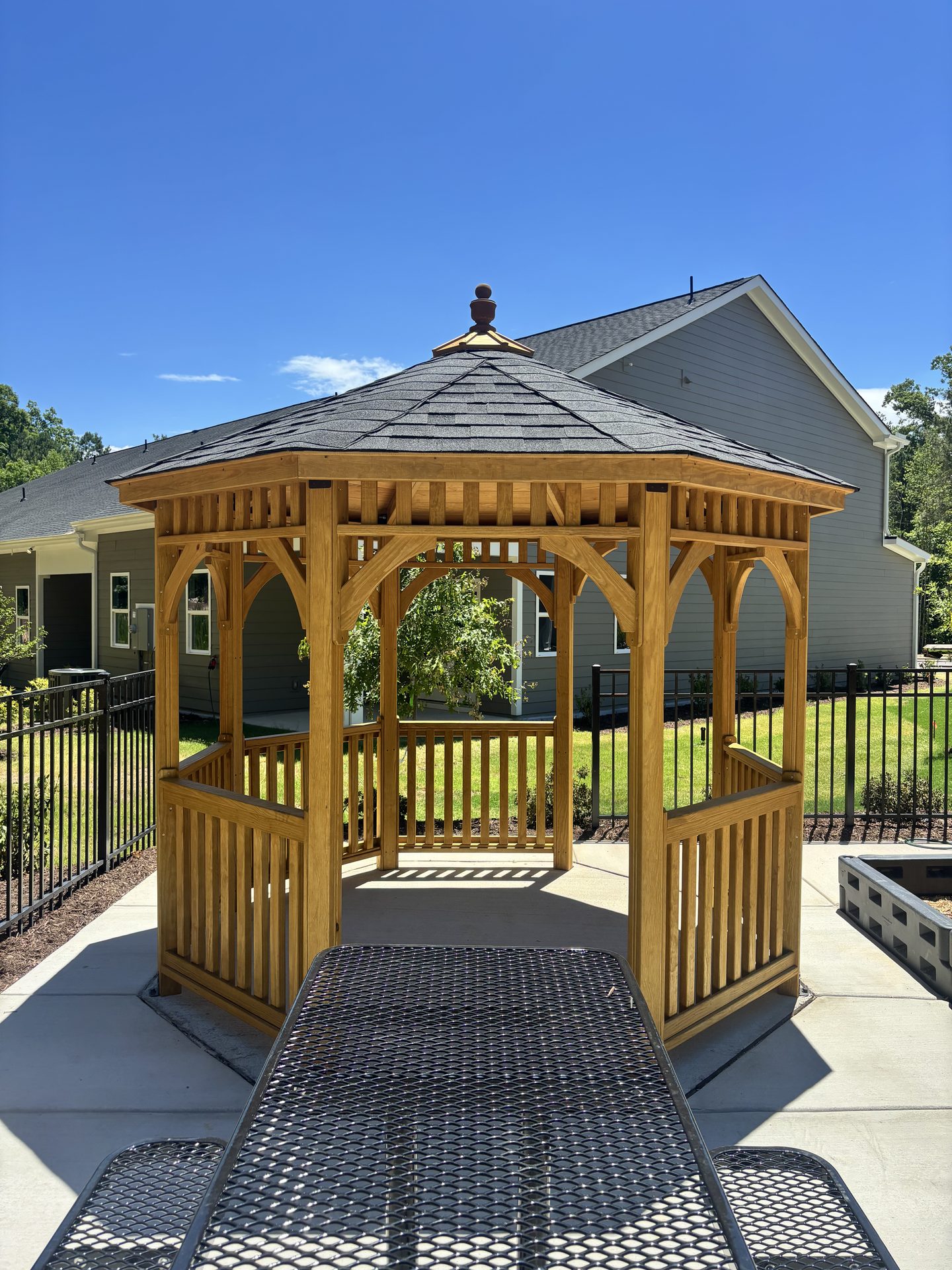 Stone kitchen island under a timber pavilion overlooking a pool